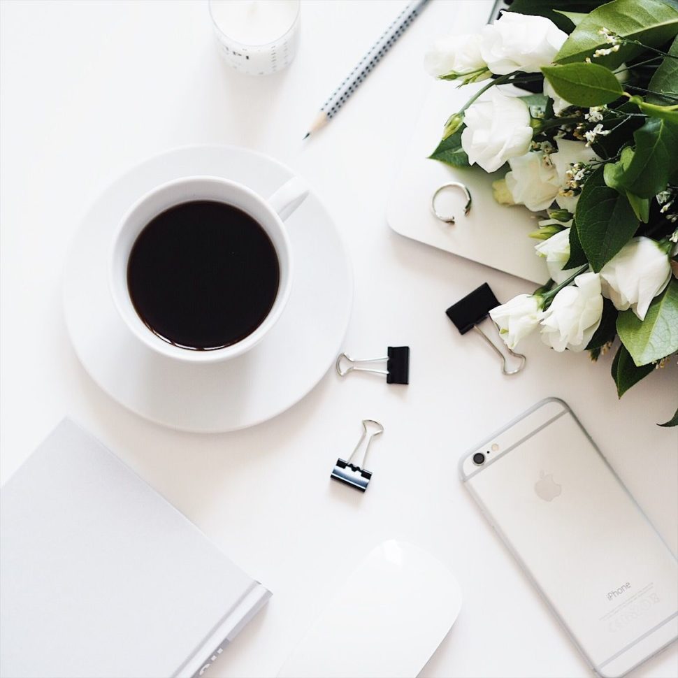 Flatlay s kávou, bílými růžemi, knížkou a iphonem