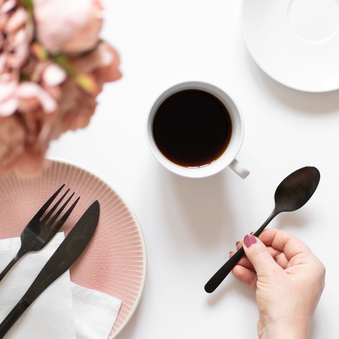 Flatlay s kávou, růžovým talířkem a černými příbory