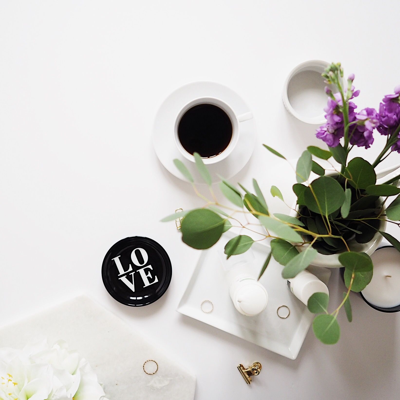Flatlay with coffee, violet flowers and little black LOVE plate
