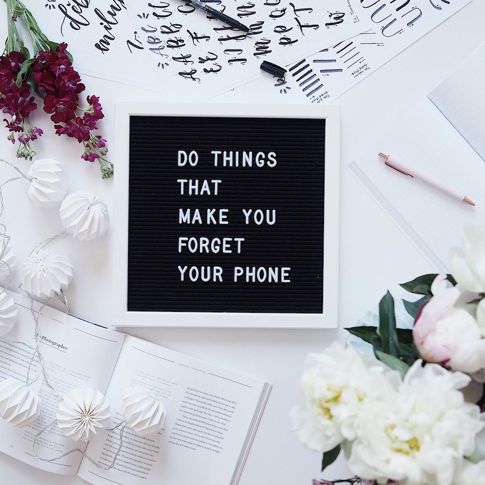 Flatlay fotka s písmenkovou tabulí s nápisem "Do things that make you forget your phone"