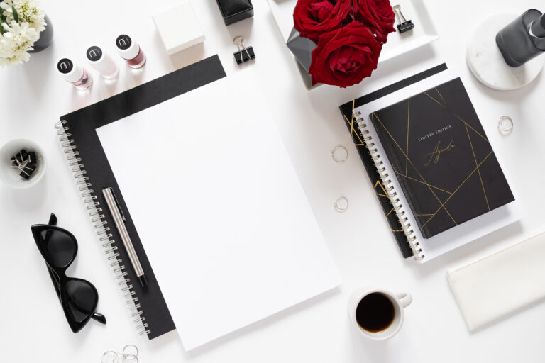 flatlay fotografie shora s černými bloky, bílým papíre, červenými růžemi a kávou na stole